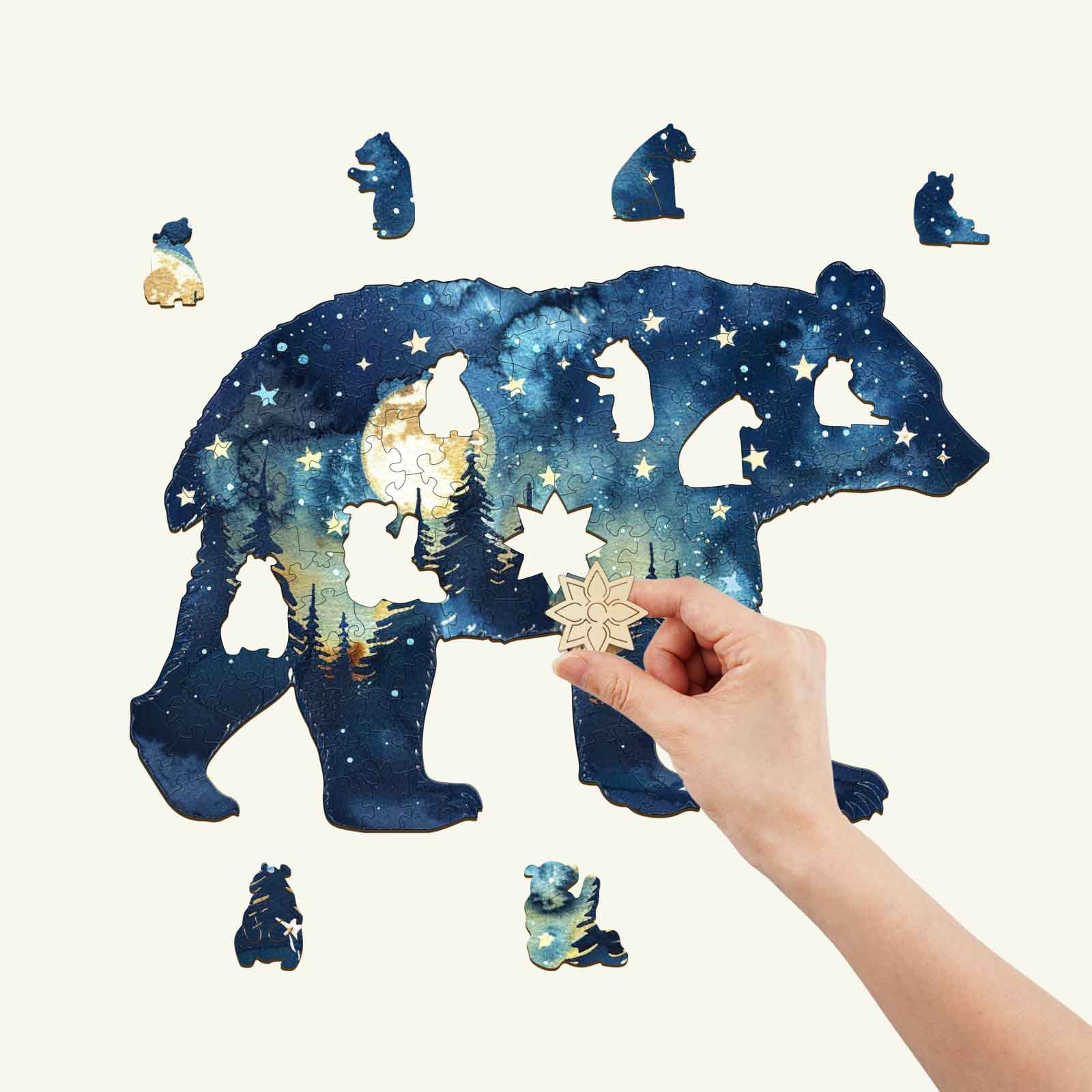 Person assembling the Astral Bear wooden jigsaw puzzle against a starry night background, enhancing focus and fun.