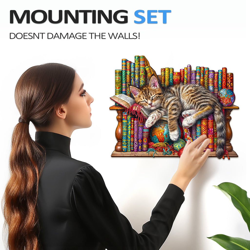 Person mounting a colorful jigsaw puzzle of a sleeping cat on the wall, showcasing the no-damage design.